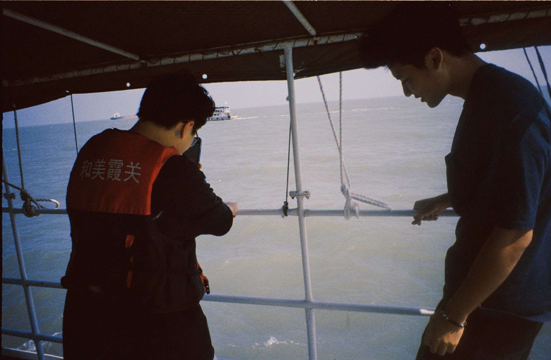 Two people standing under a boat canopy