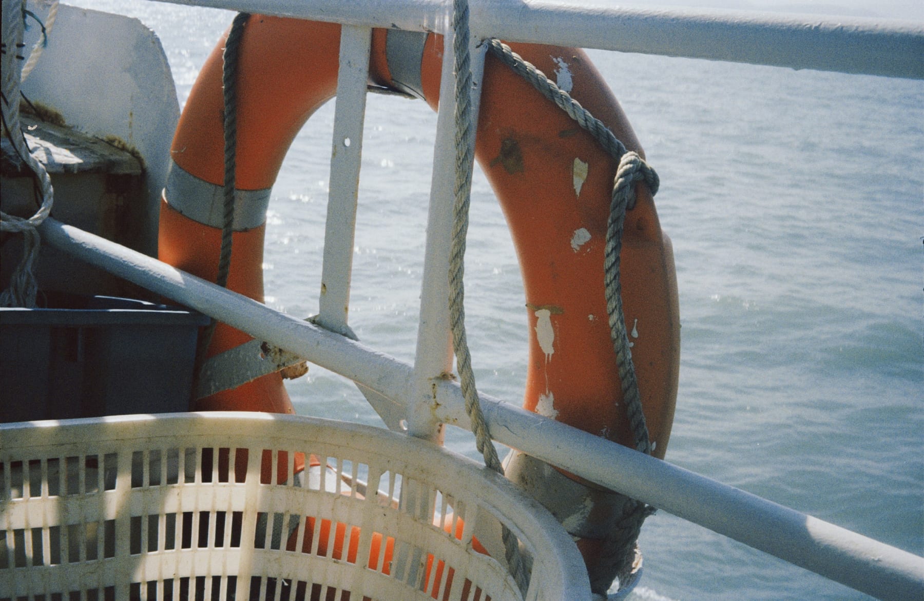 An orange life ring hanging beside a boat railing