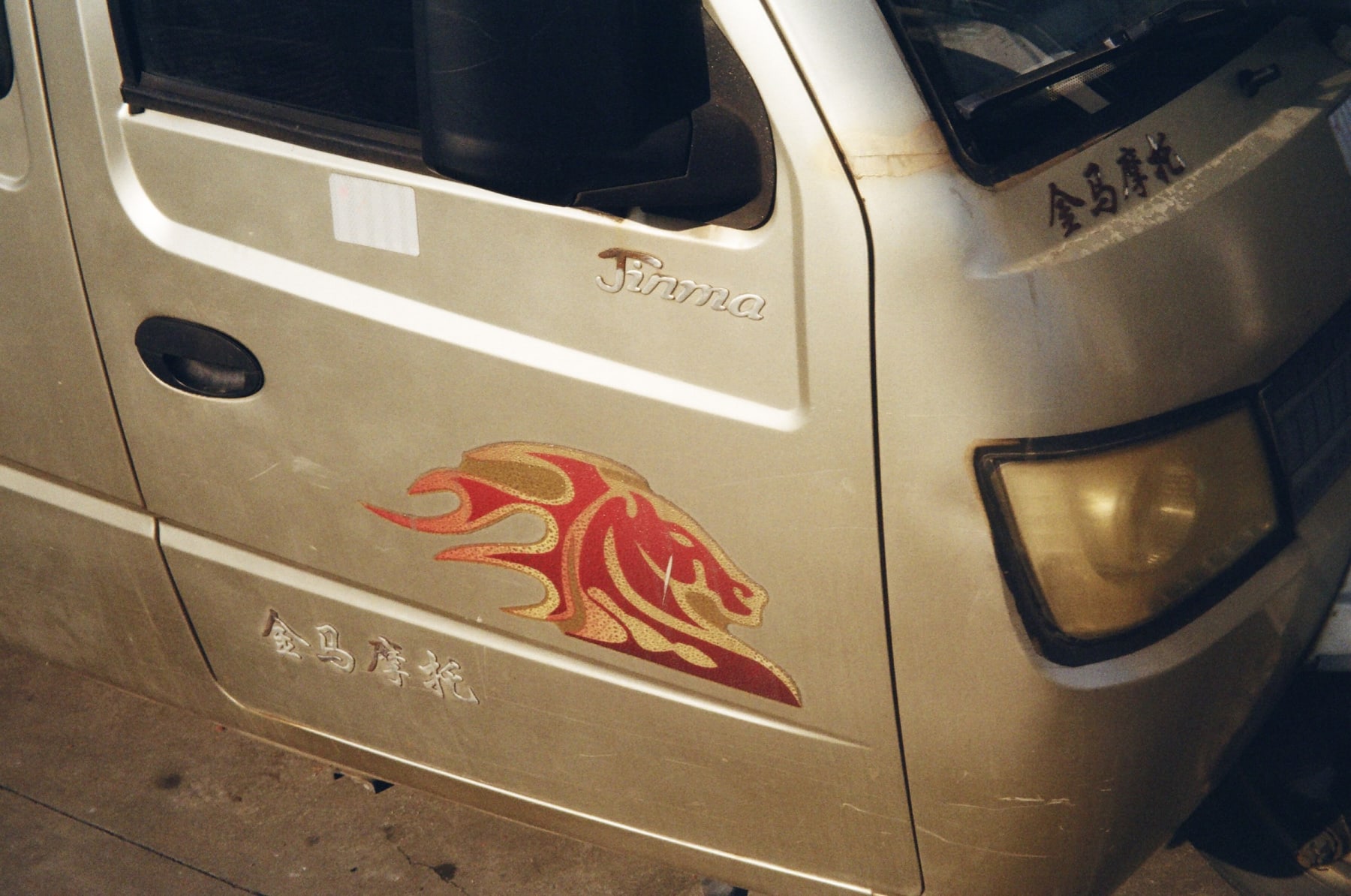 A golden truck with a red horse decal