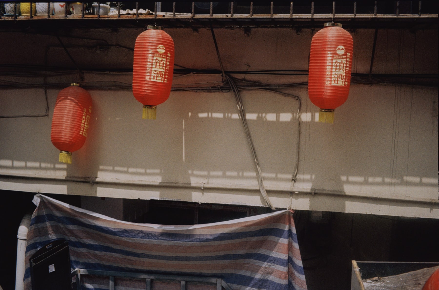 Red lanterns hanging above a striped tarpaulin