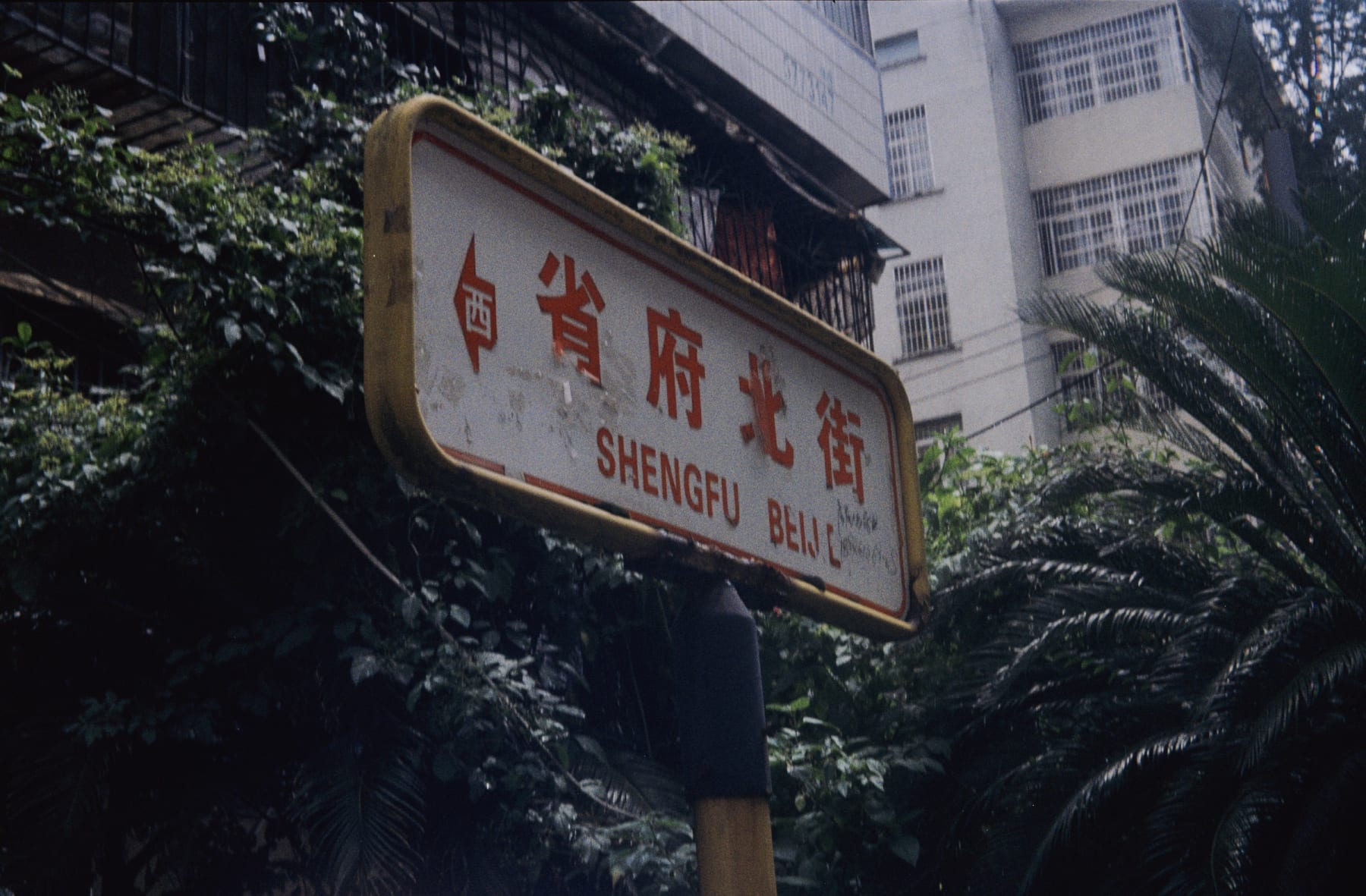 A street sign among trees and apartment buildings