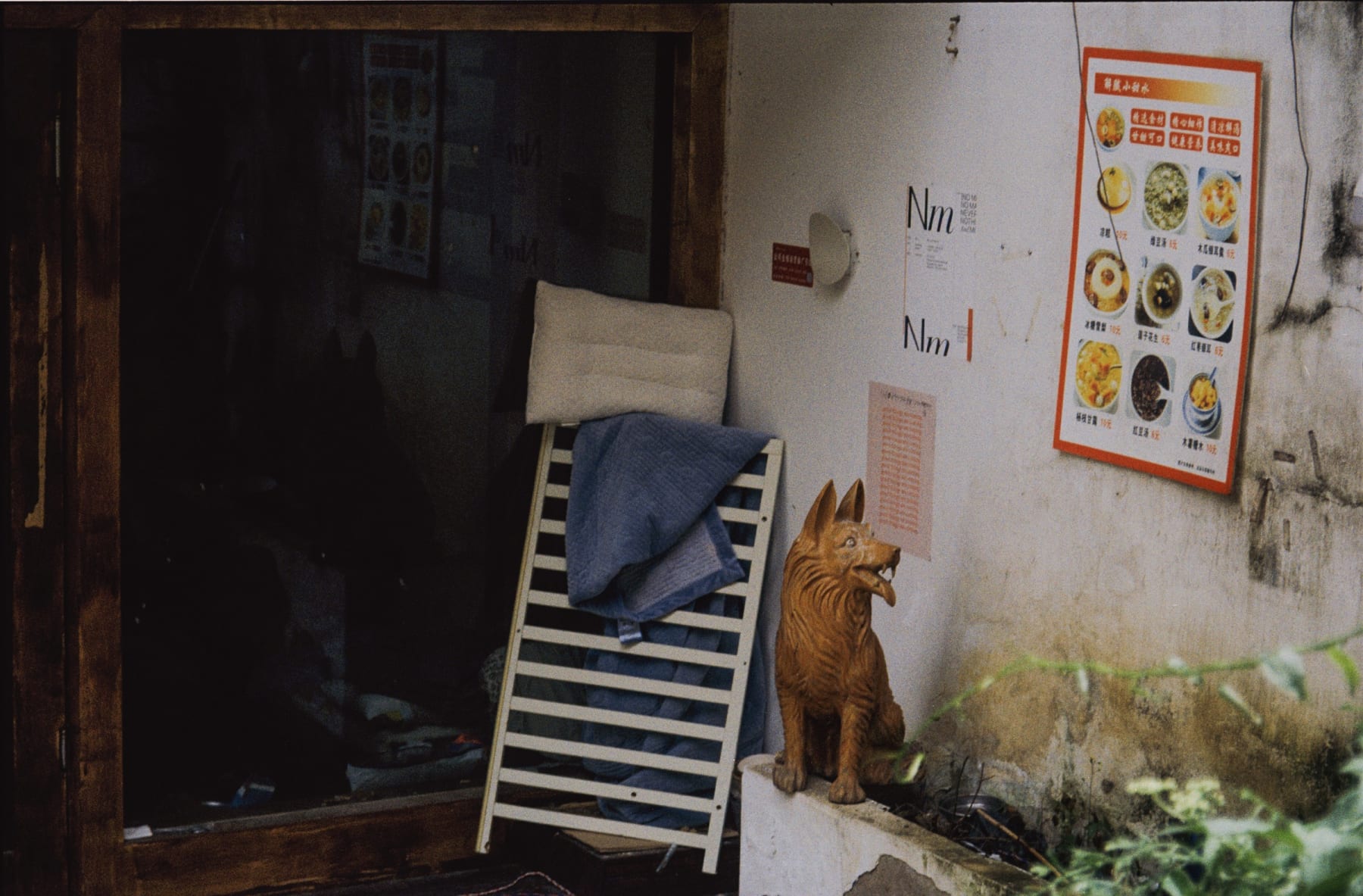 A carved wooden dog beside a chair and shop doorway