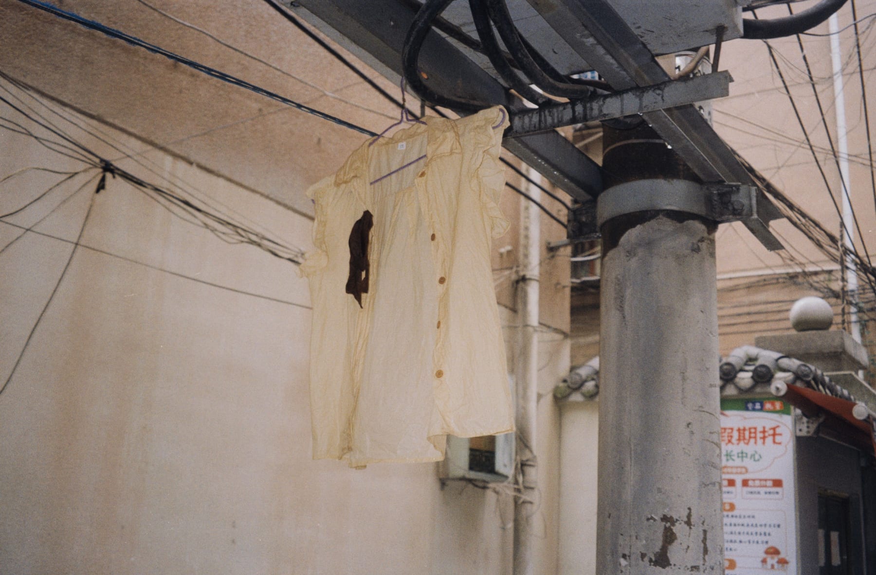 A pale shirt hanging beside a utility pole and cables