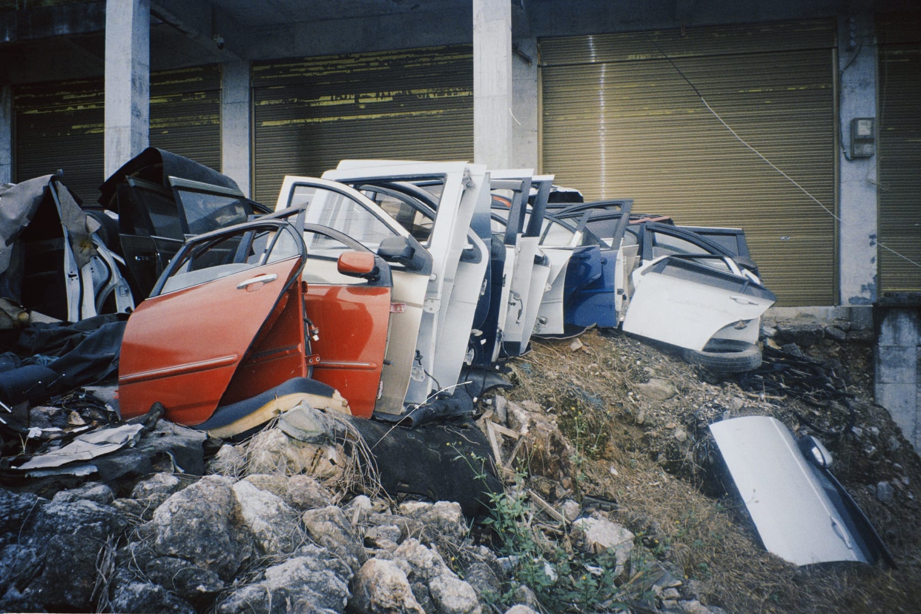 Detached car doors arranged outside closed workshops