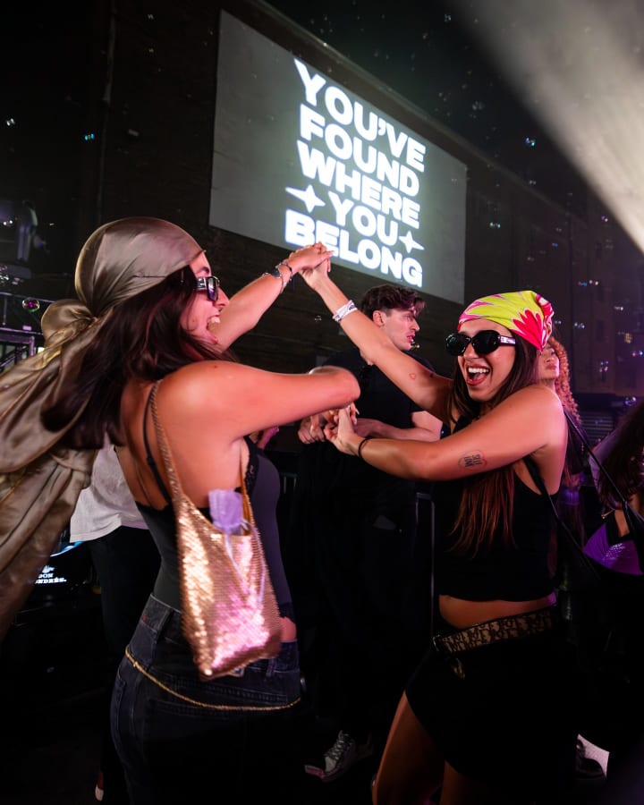 Friends dancing in front of the YOU HAVE FOUND WHERE YOU BELONG screen