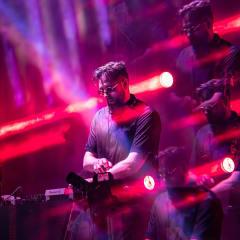 DJ at the decks under red and magenta moving-head lighting