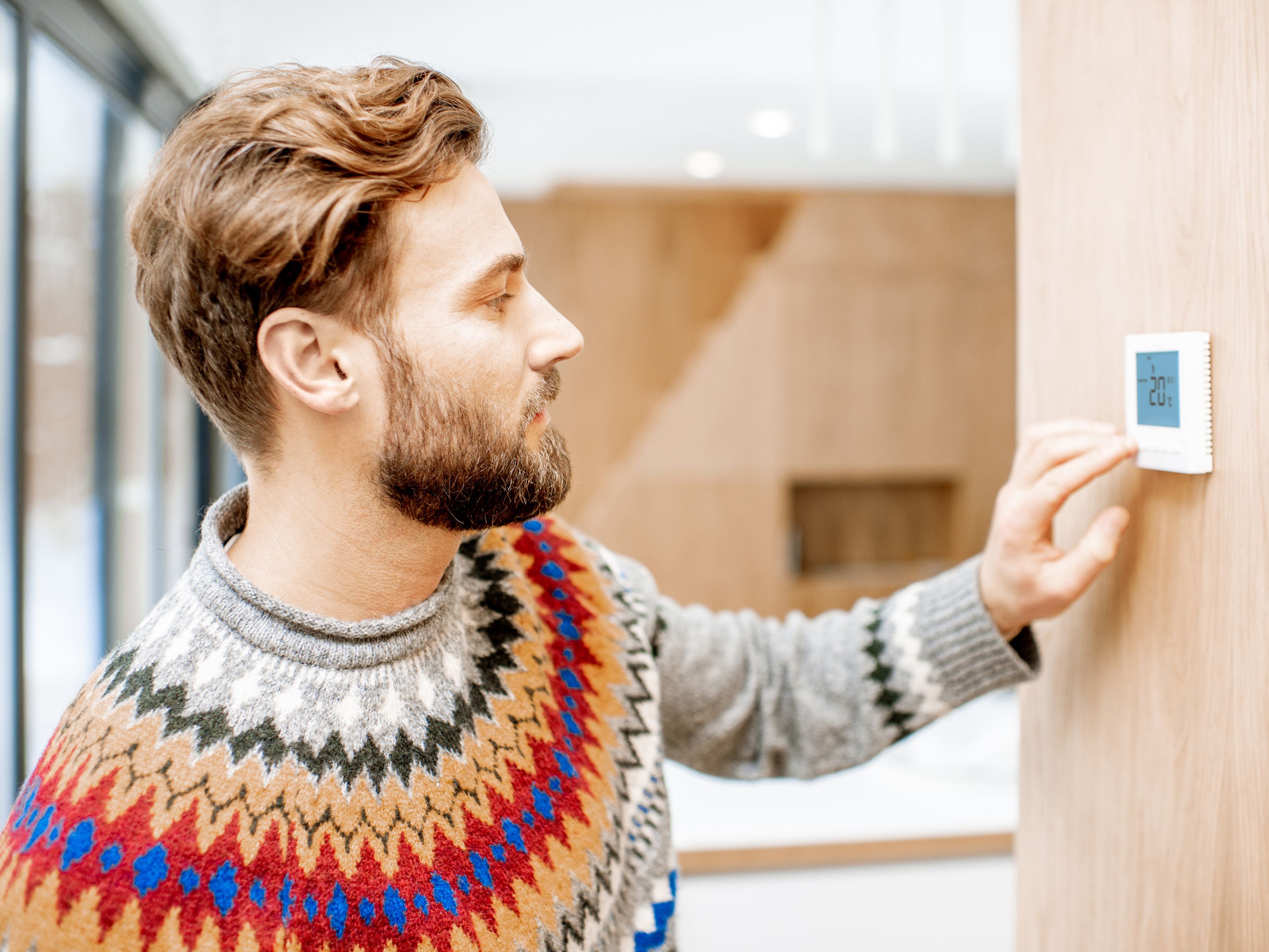 Image of a man adjusting a thermostat.