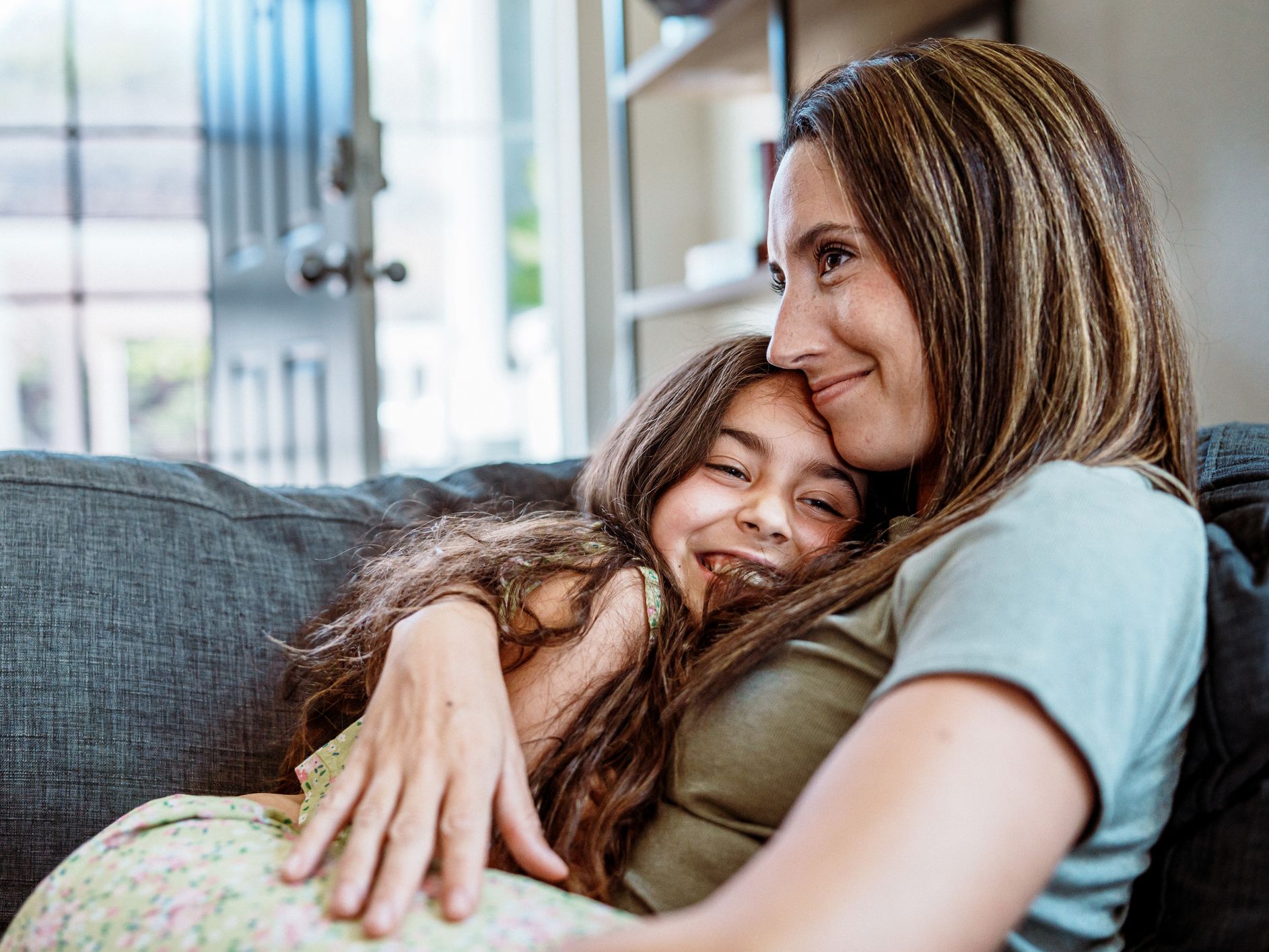 Woman and child embracing on a couch.