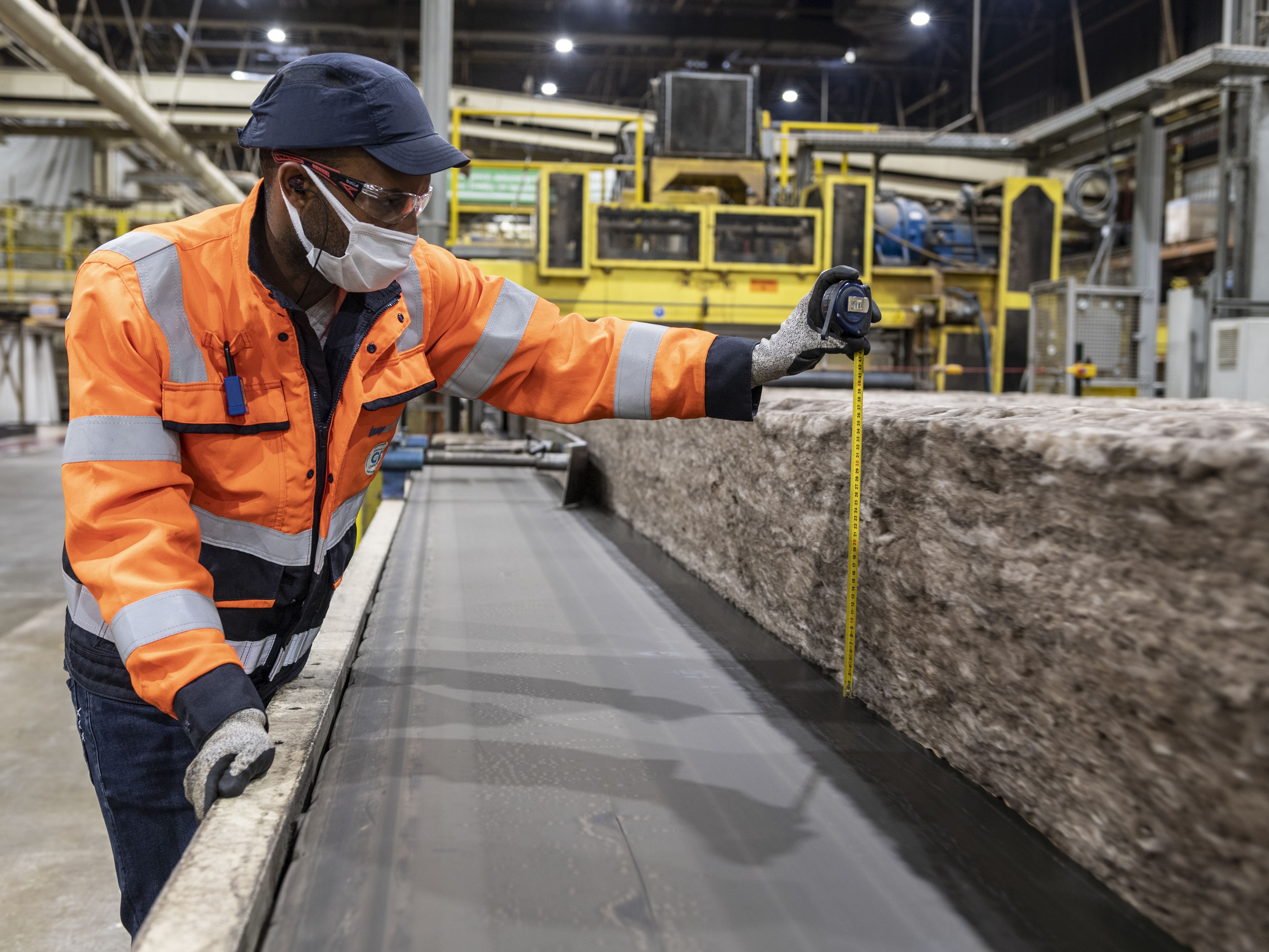 Man measuring a slab of mineral wool insulation.