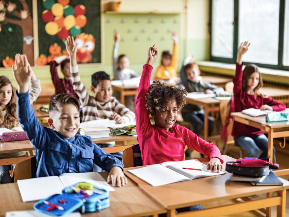 Students in a classroom raising their hand.