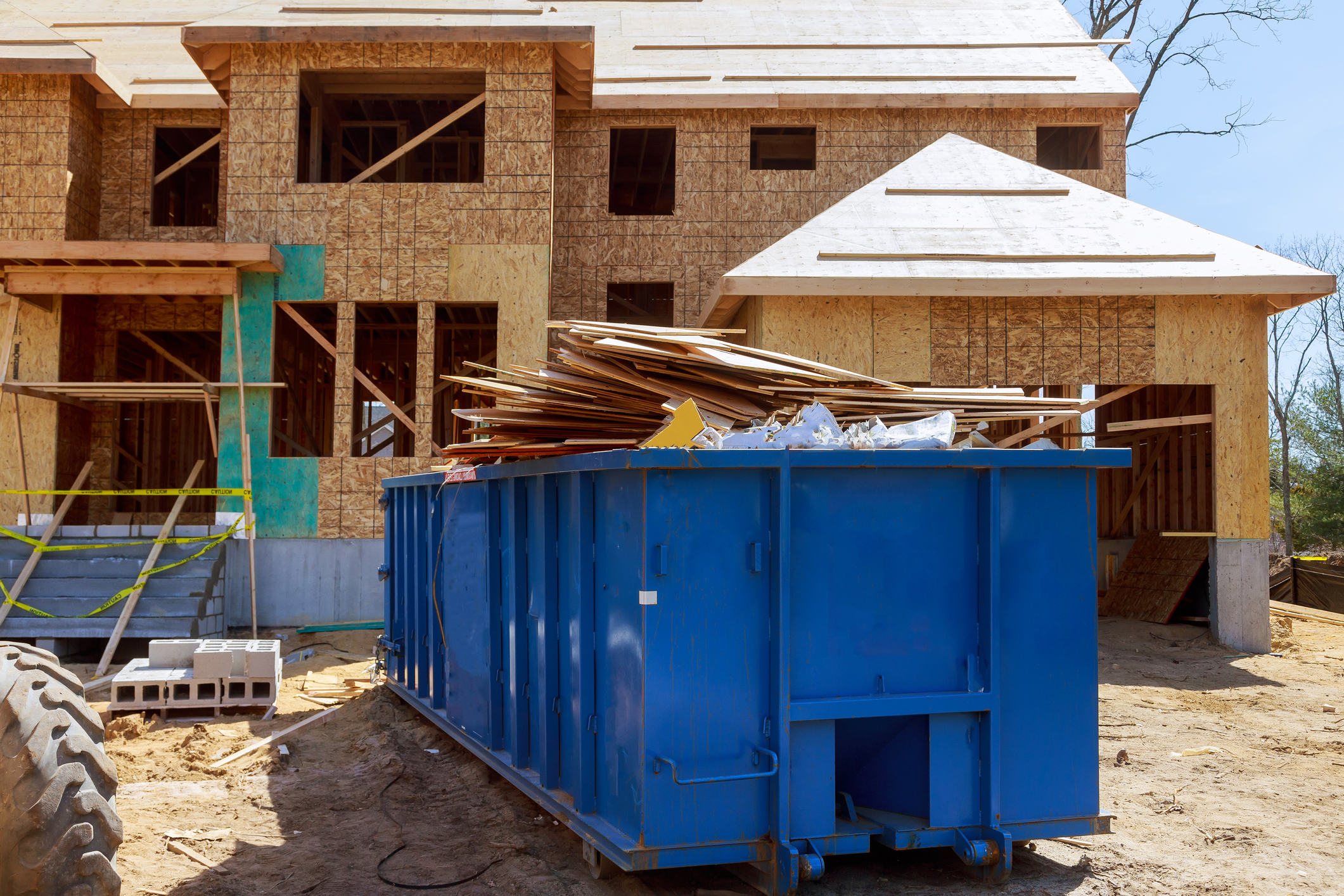Construction site with a dumpster collecting wood and debris to manage construction waste