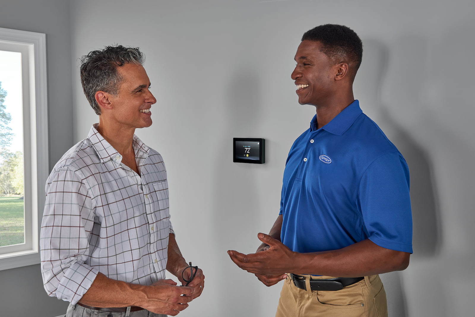 Bryant technician talking with homeowner while checking air filter and furnace
