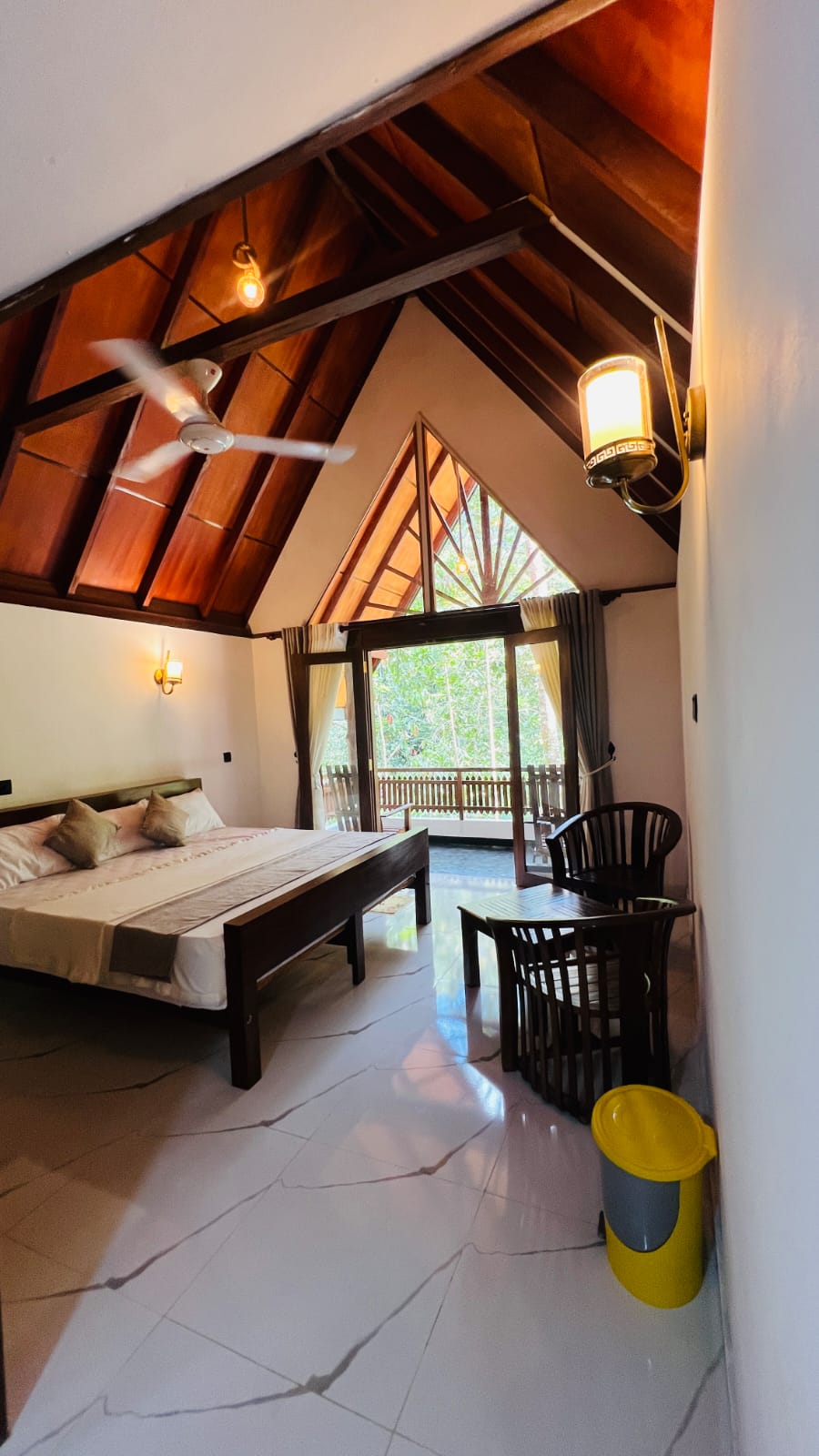 Warm wooden bedroom with balcony looking out to lush green forest