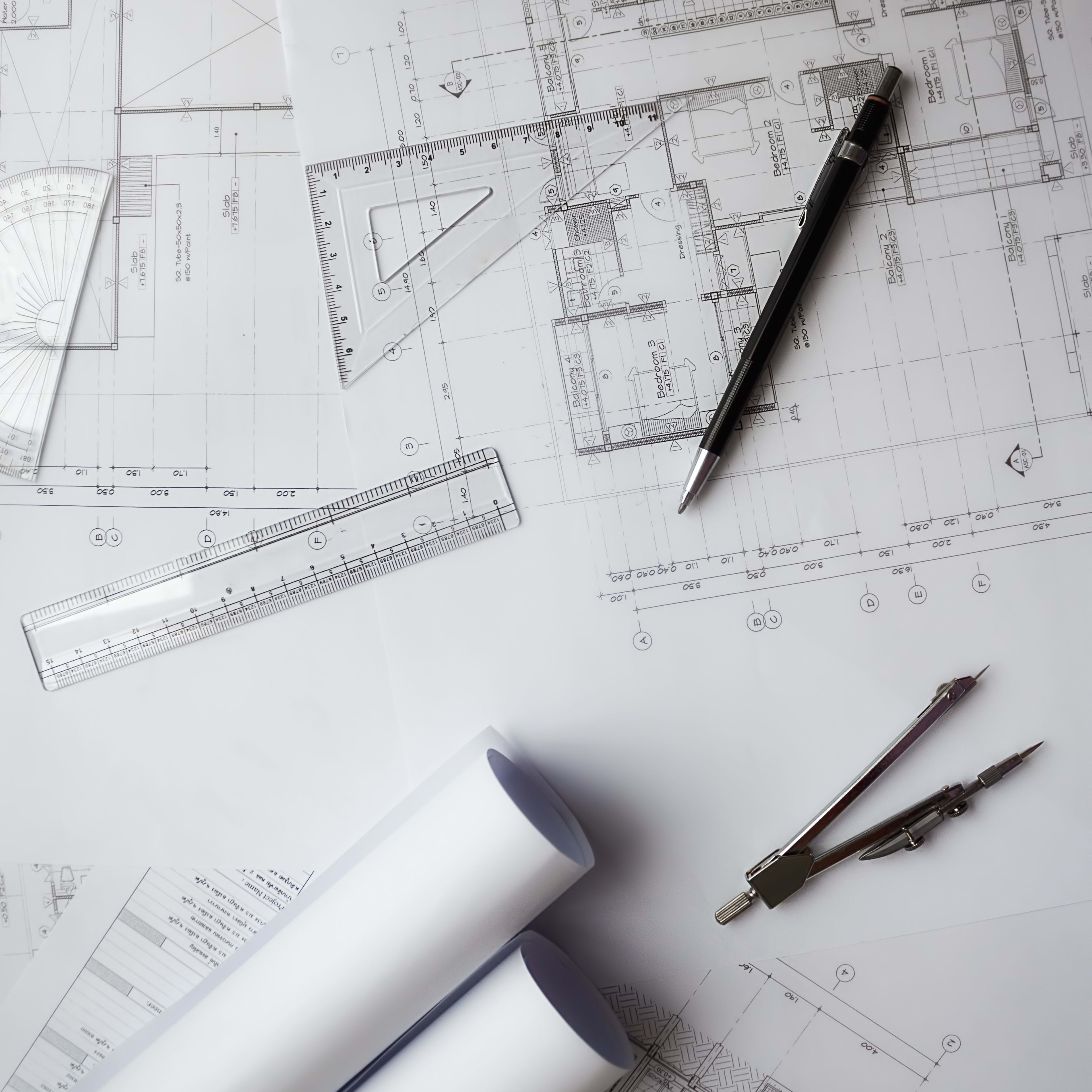 Architektenpläne und Werkzeuge wie Lineal, Kompass und Stifte, auf einem Schreibtisch arrangiert.