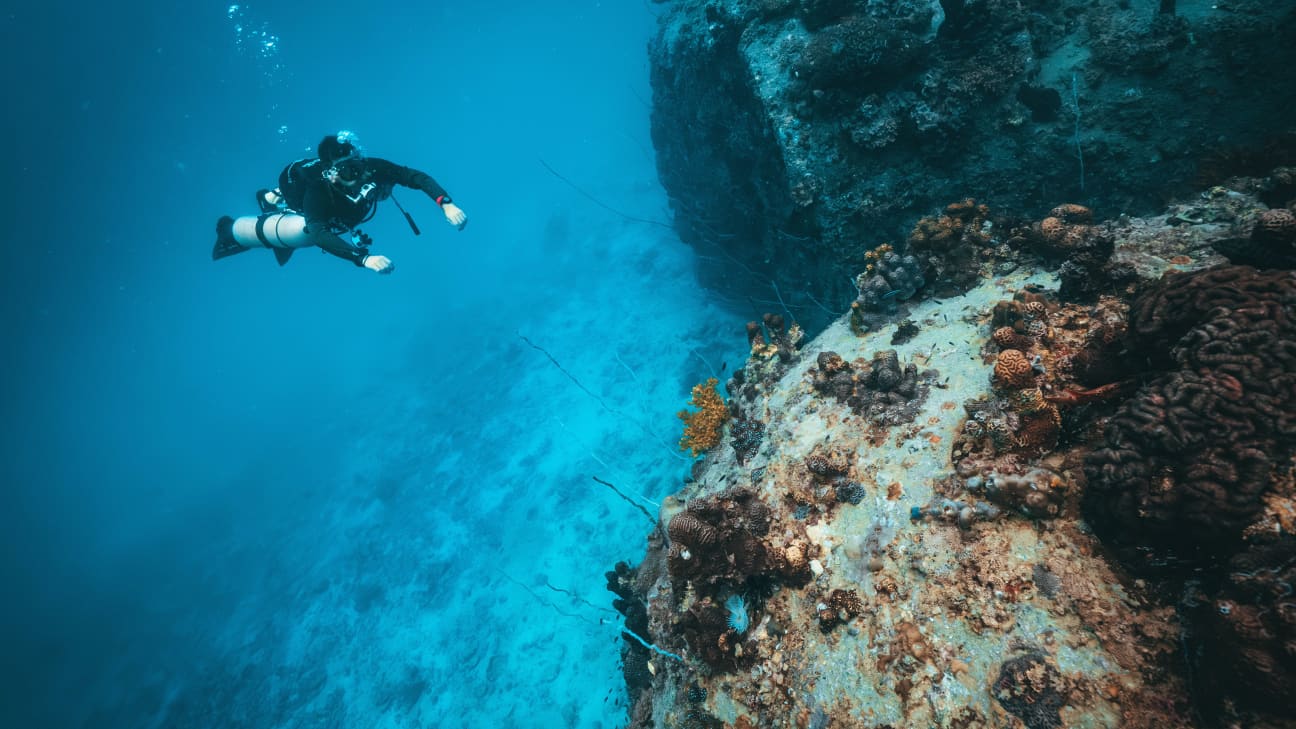Koh Tao Divers technical diver hovering in open water next to corals and rocks, practicing buoyancy