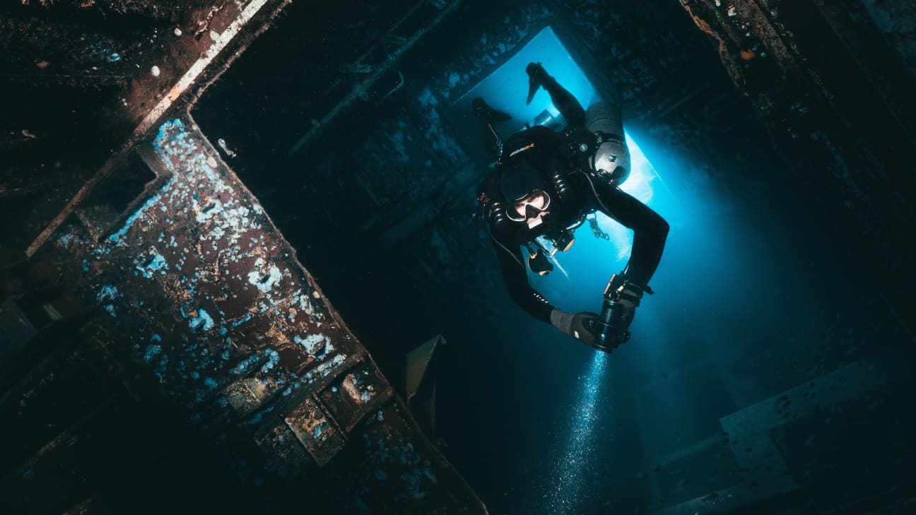 Koh Tao Divers technical diver exploring inside a sunken shipwreck illuminated by dive light