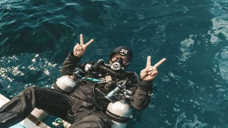Koh Tao Divers CCR diver flashing peace signs while floating on surface in full rebreather gear