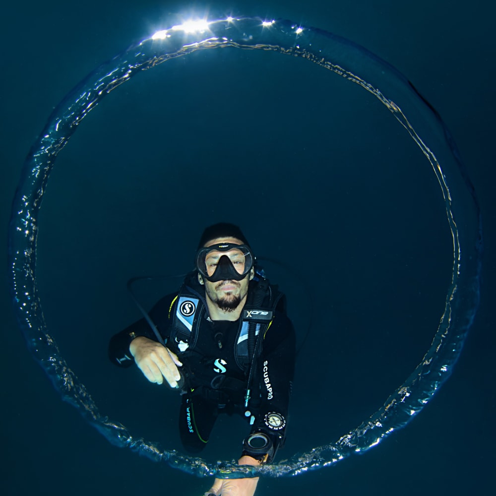 Koh Tao Divers male diver framed through a perfect underwater bubble ring during ascent
