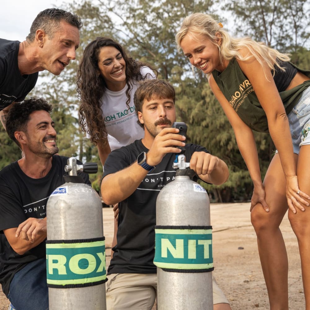 Koh Tao Divers students learning about Nitrox cylinders on the beach with instructors.