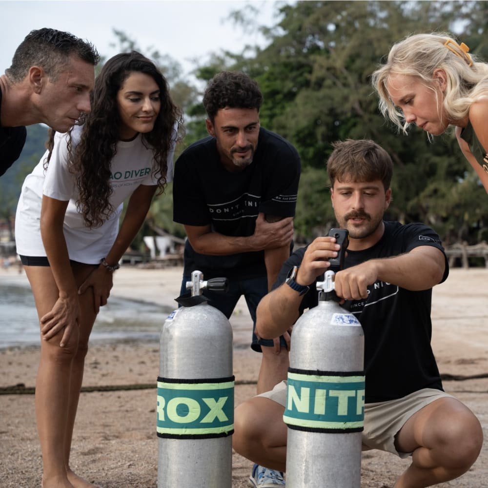 Koh Tao Divers group measuring oxygen content of Nitrox tanks during beachside training.