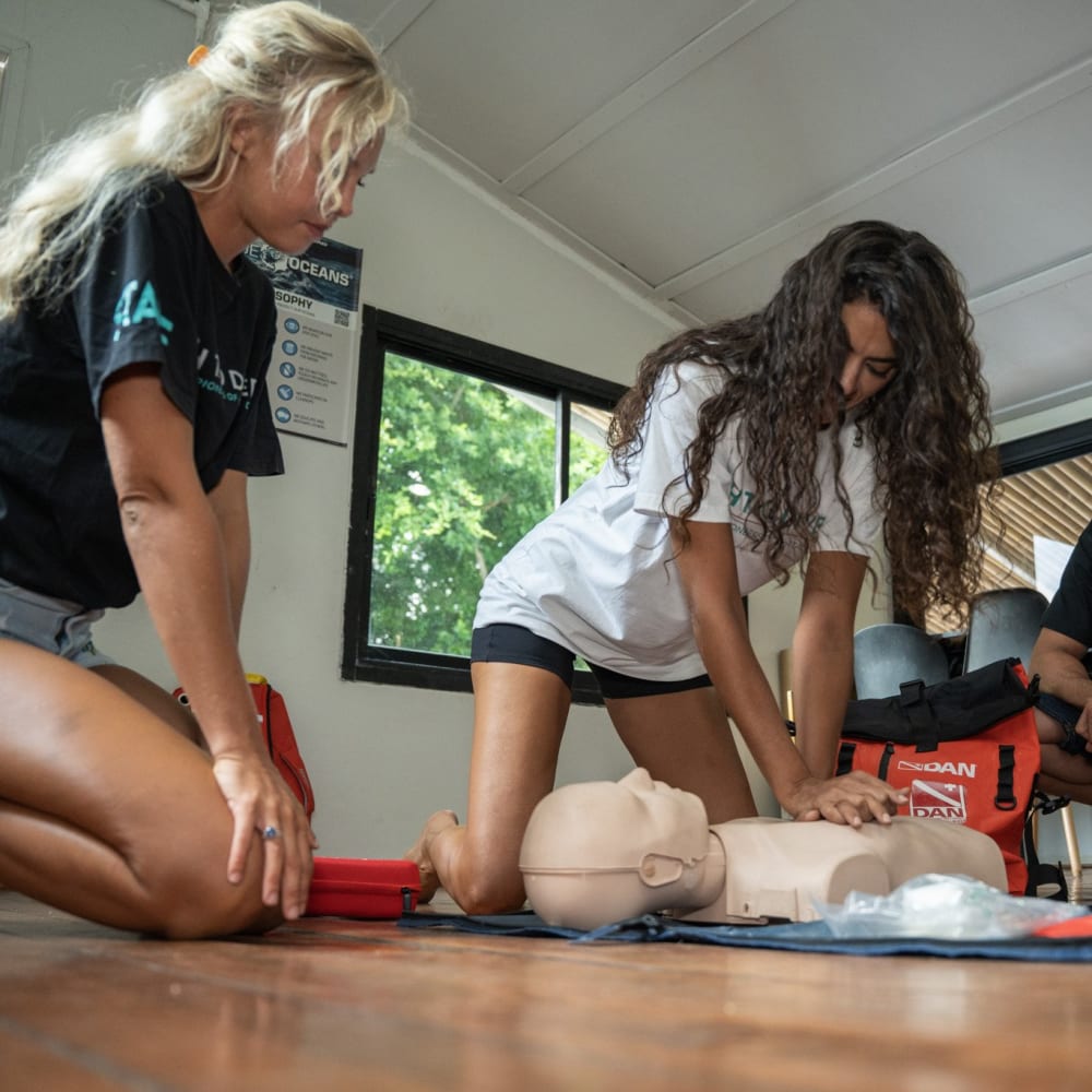 Koh Tao Divers CPR class with students observing hands-on demonstration on a dummy.