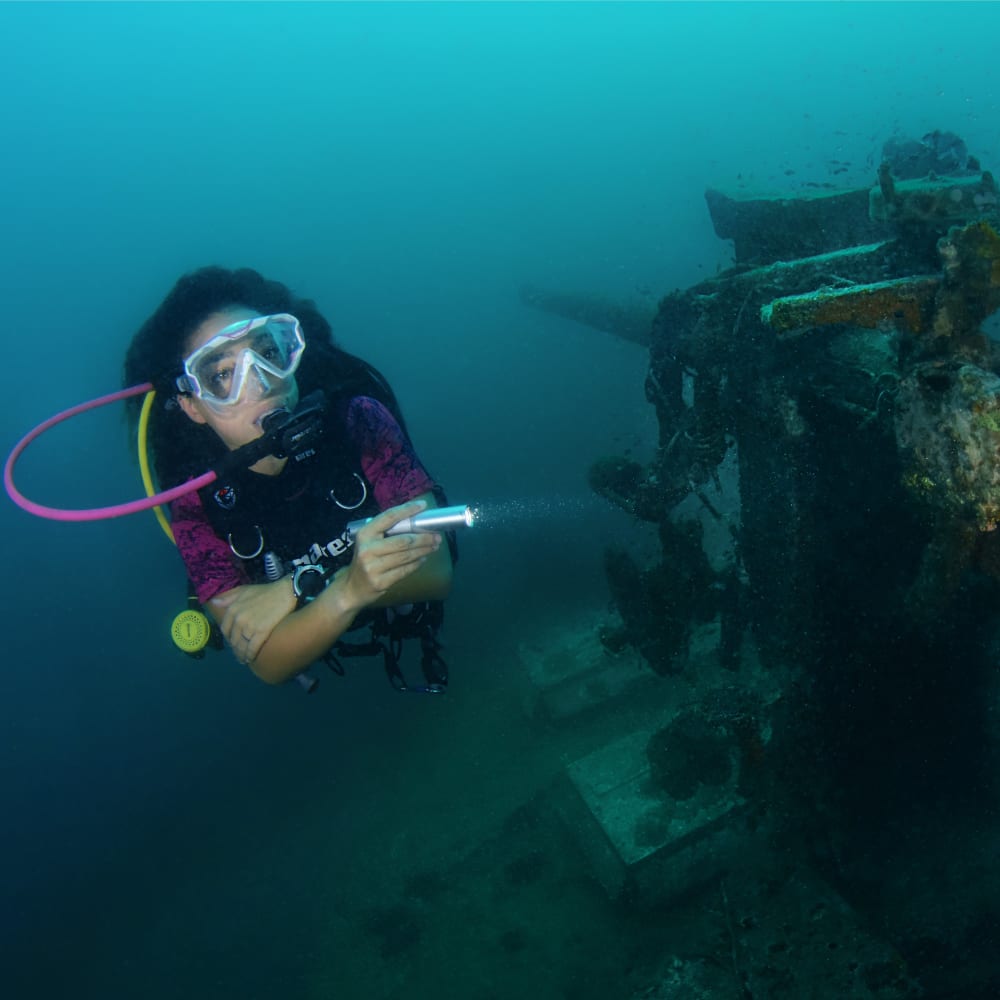 Koh Tao Divers female diver inspecting corroded artillery of the HTMS Sattakut