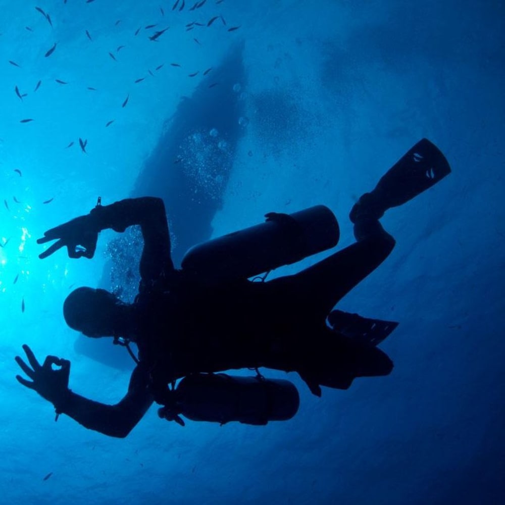 Koh Tao Divers silhouette of diver giving OK hand signal beneath dive boat.