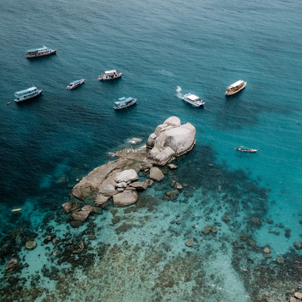 Koh Tao tropical island bay with multiple dives boats and rocks