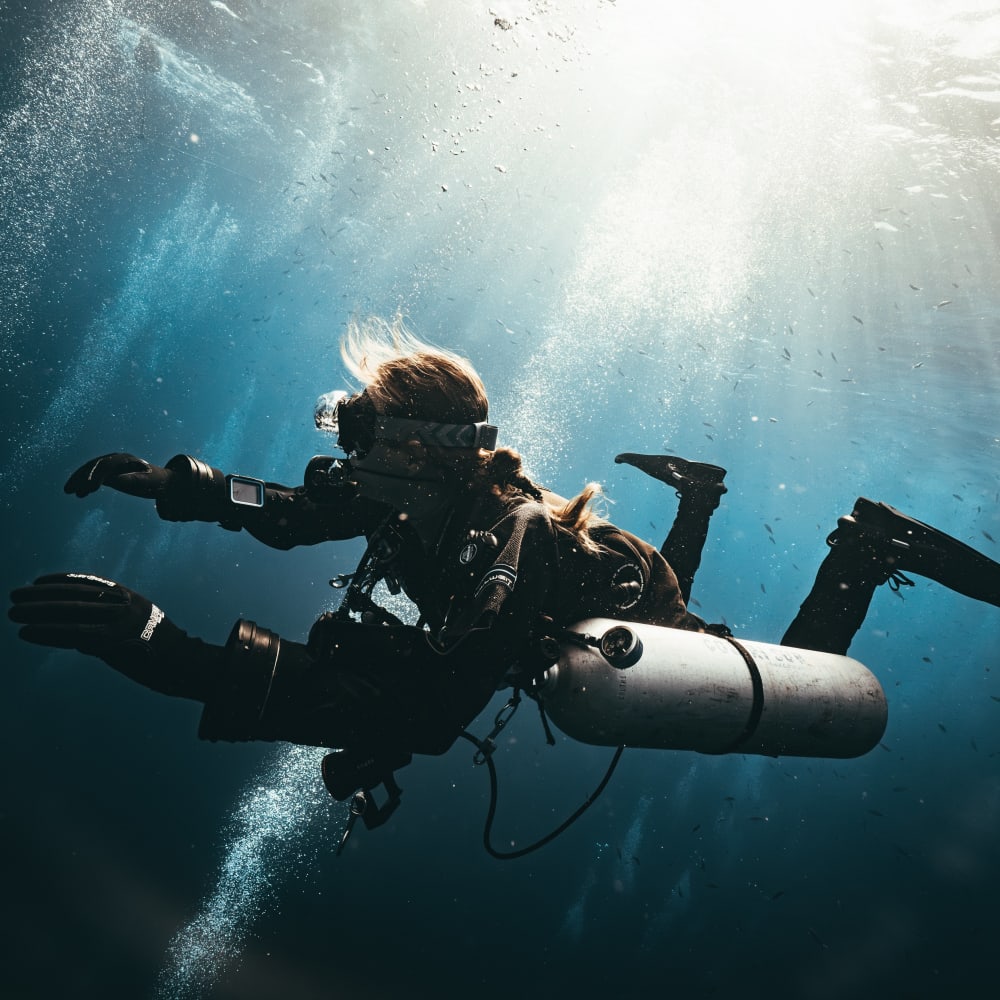 Koh Tao Divers female technical diver gliding through open blue water with sunlight above