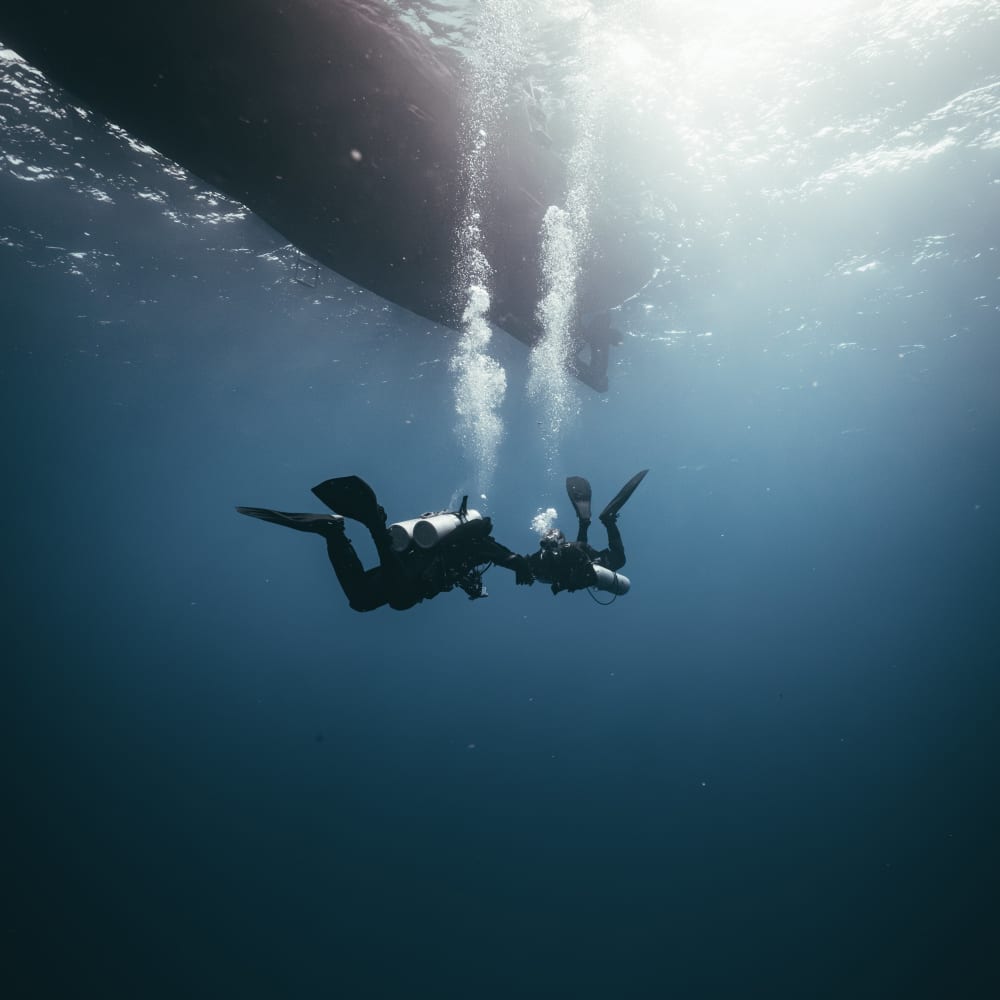 Koh Tao Divers two technical divers silhouetted beneath a dive boat ascending to the surface
