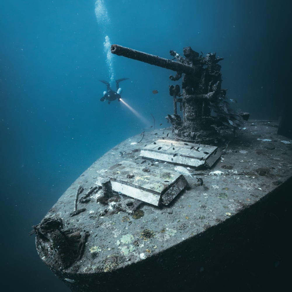 Koh Tao Divers technical diver approaches the bow of a sunken shipwreck with large cannon