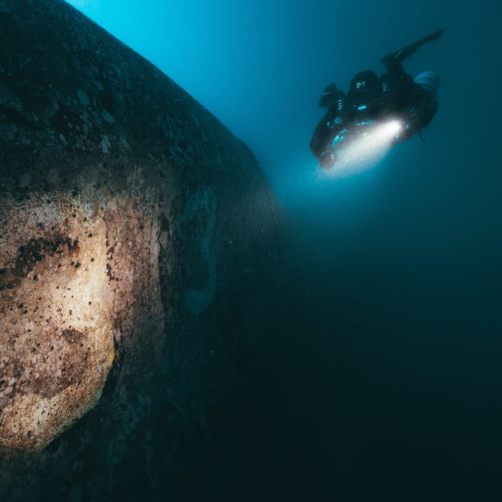Koh Tao Divers rebreather diver diving next to a coral wall with flashlight