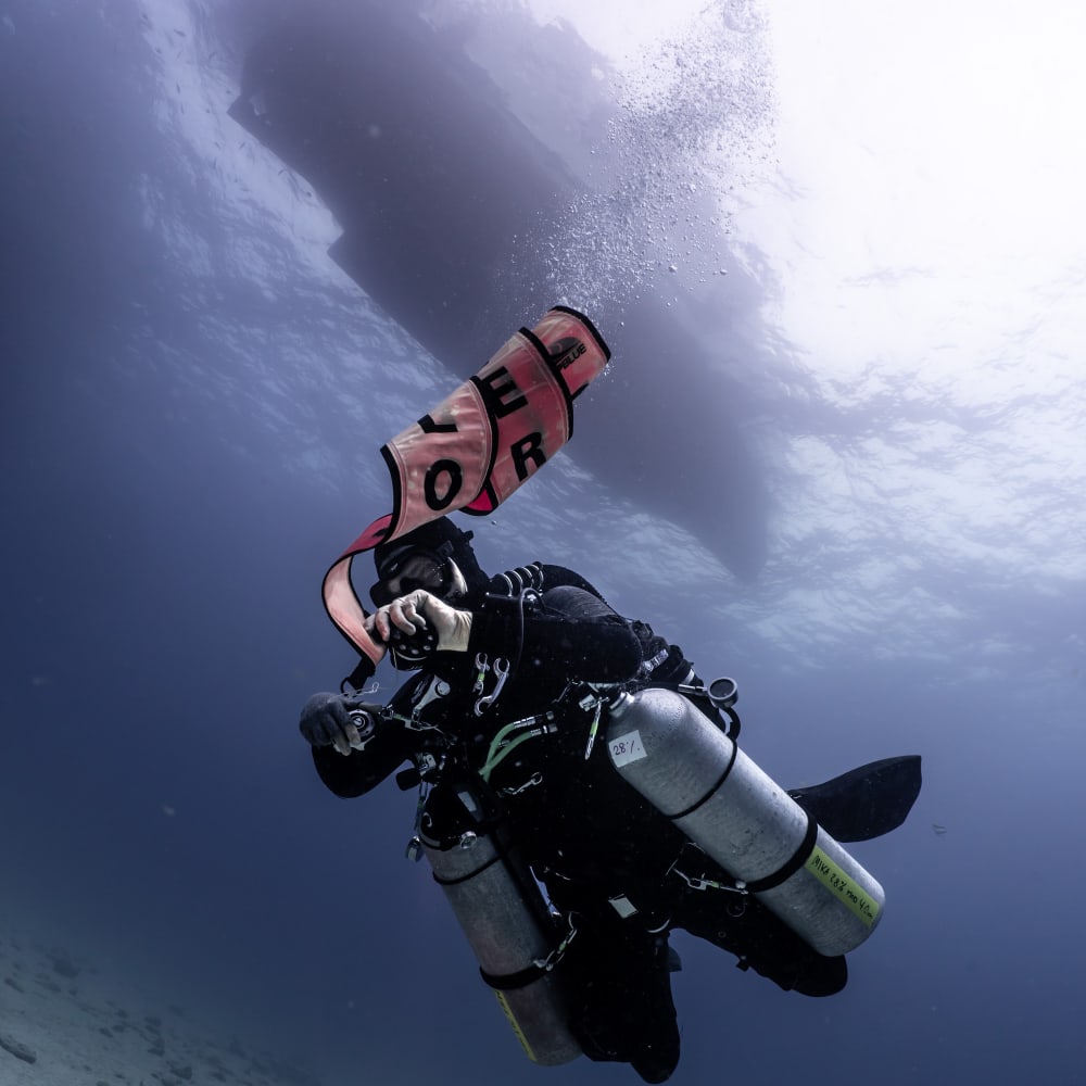 Koh tao divers CCR diver deploying floating safety device with boat above 