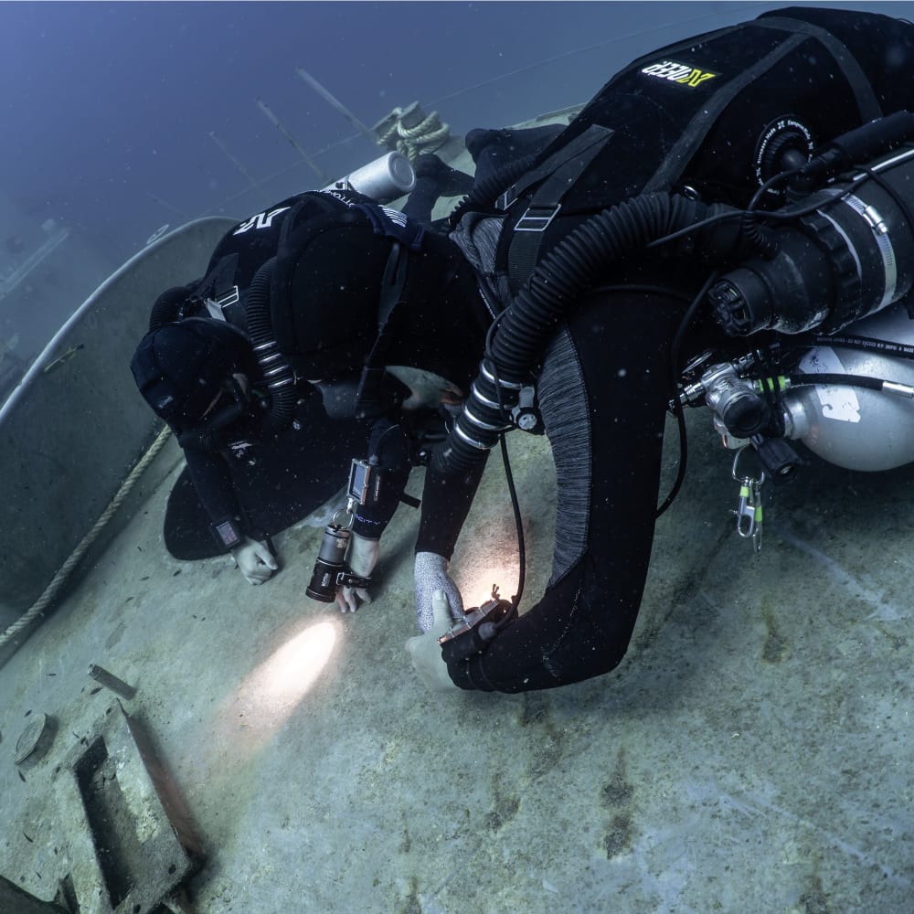 Koh Tao Divers rebreather divers inspecting a shipwreck underwater with flashlights