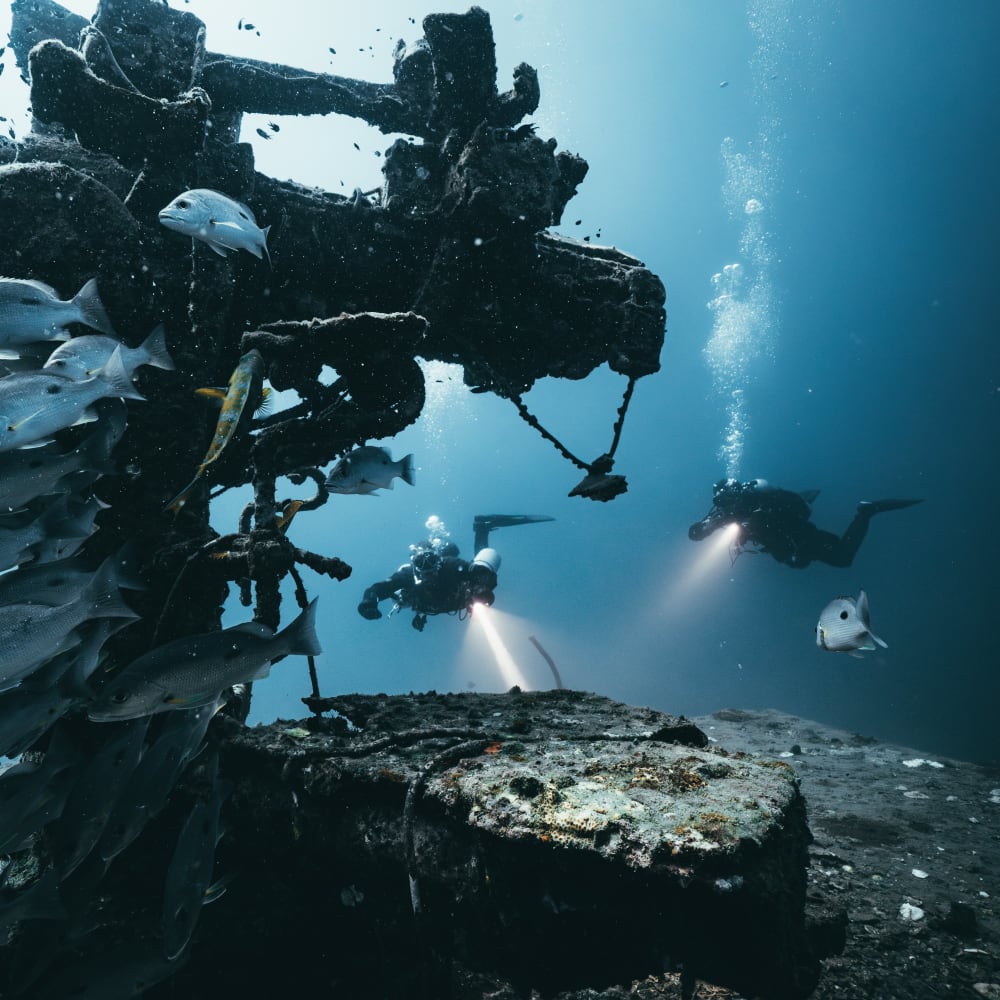 Koh Tao Divers wreck diver entering a tight hatchway inside the HTMS Sattakut with a flashlight
