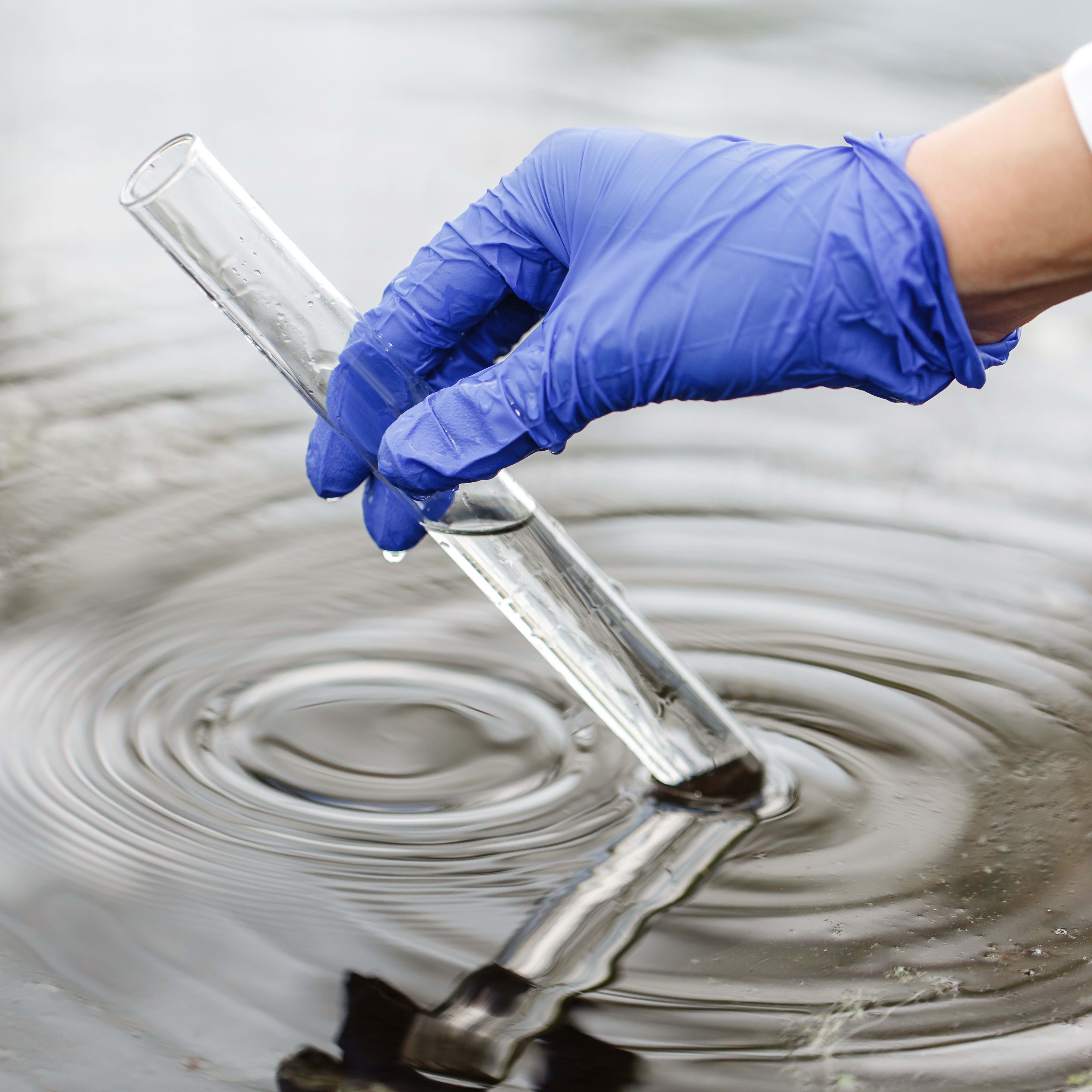 Stimmungsbild einer Wasserqualitätskontrolle, bei der eine Wasserprobe aus der Wasserquelle entnommen wird.