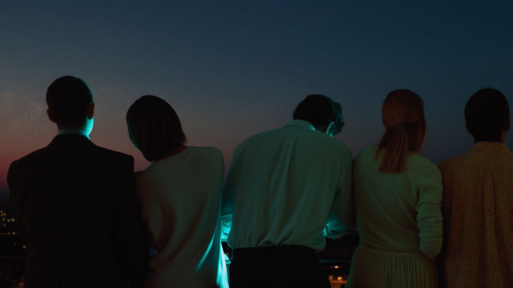 Un gruppo di amici di spalle su una terrazza al tramonto