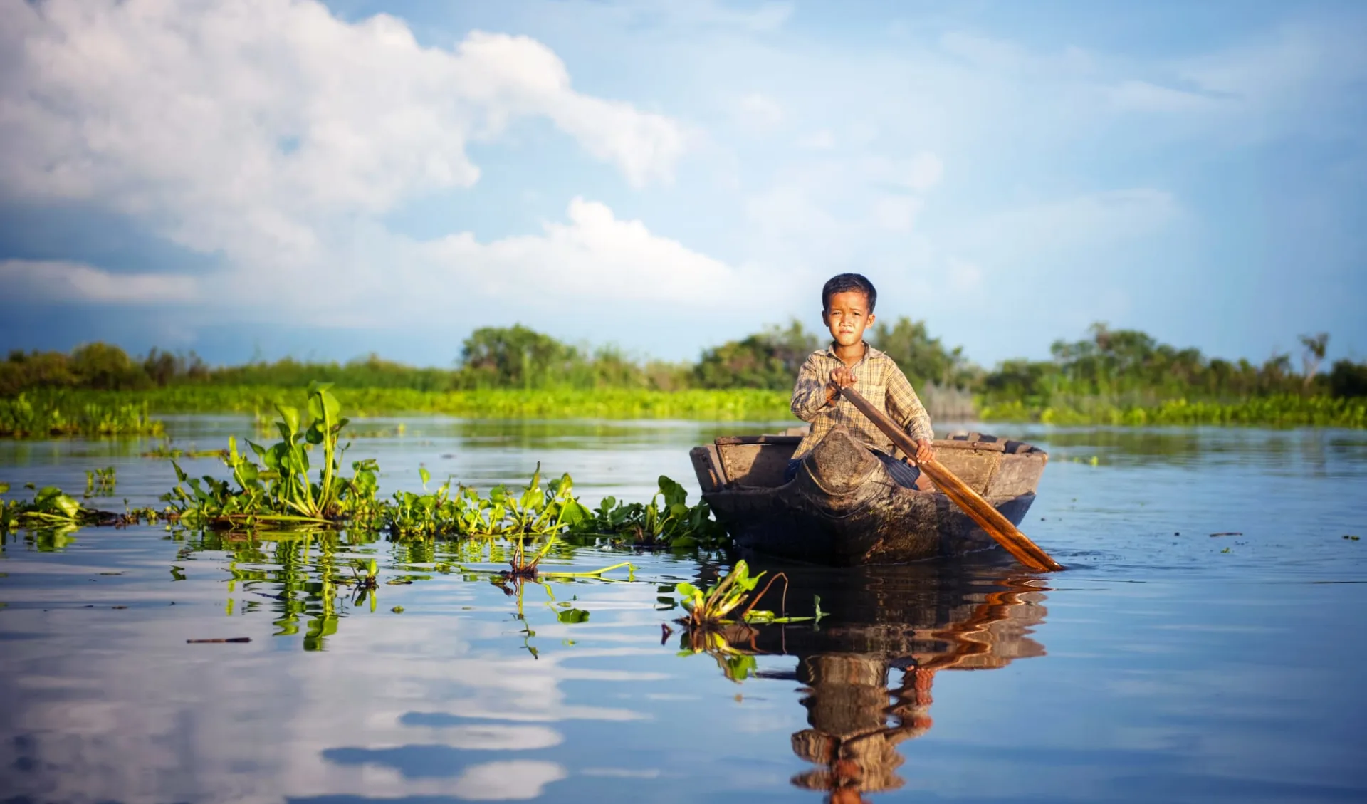 Flusskreuzfahrt nach Saigon ab Siem Reap: Tonle Sap boy travelling by boat to his floating village