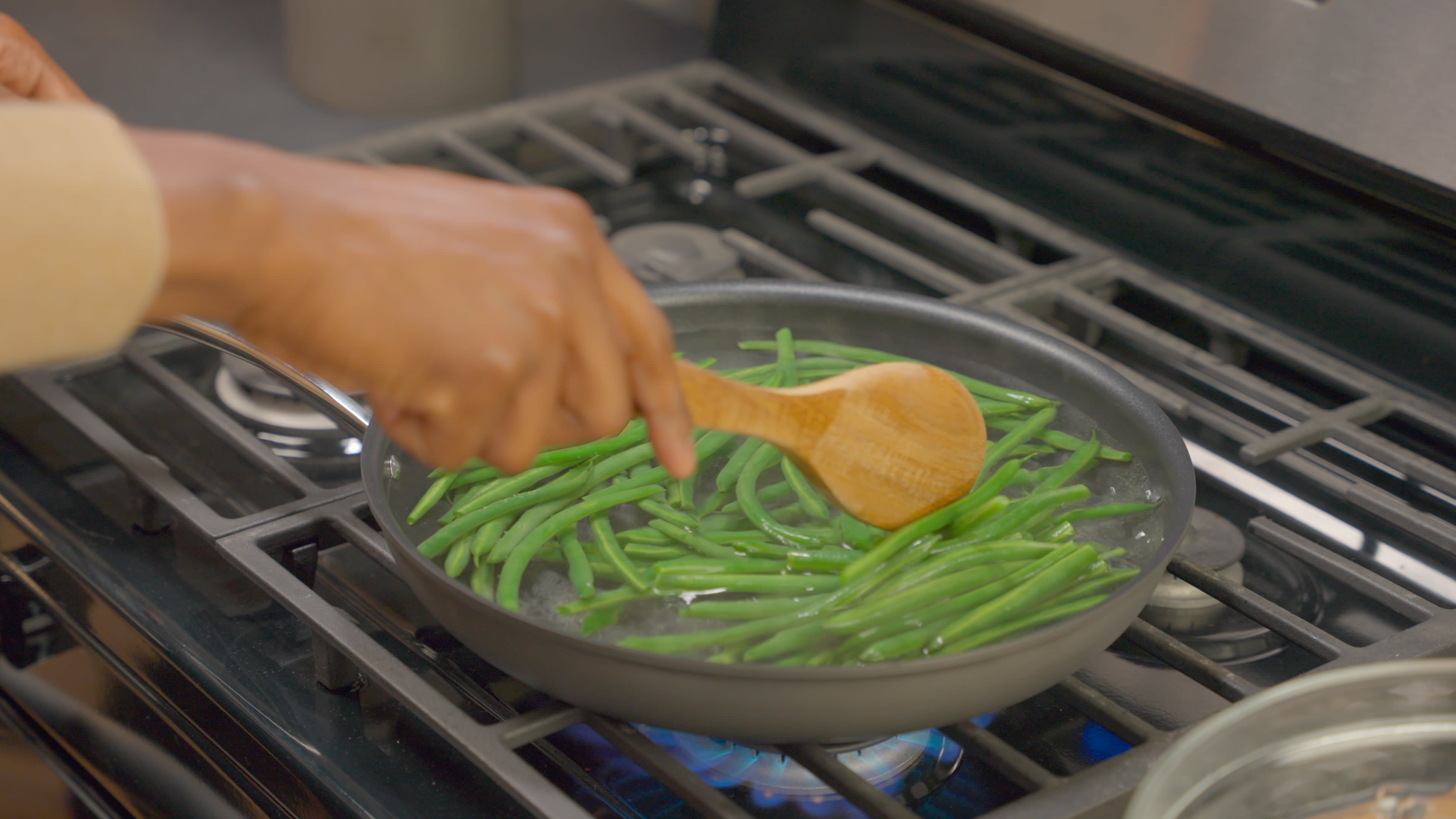 Green beans simmering in water in a large saucepan.