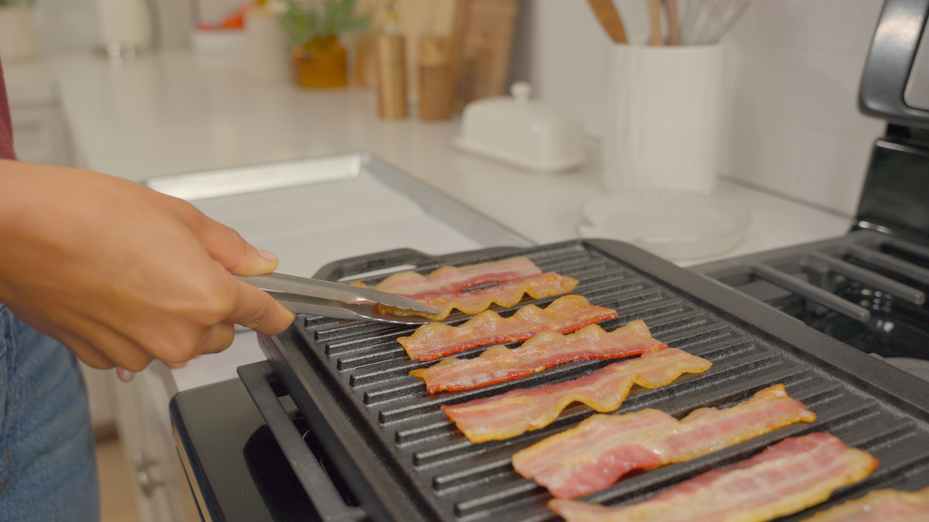 Prepare bacon by slicing each piece in half, then laying them on a pan.