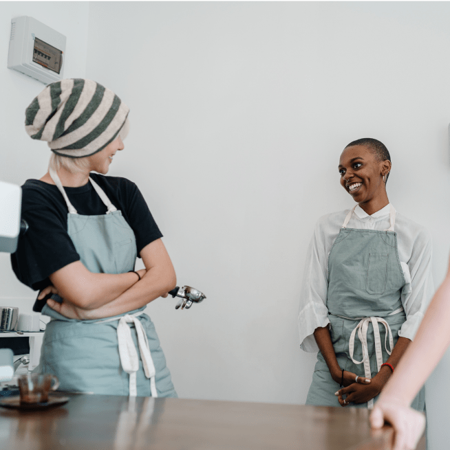 Two chefs standing up in a kitchen talking to each other