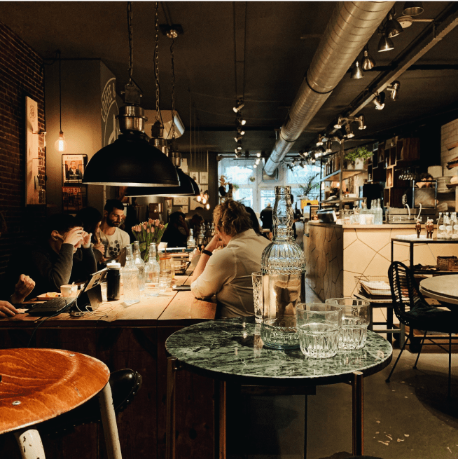 People sitting at a long wooden table inside of a restaurant