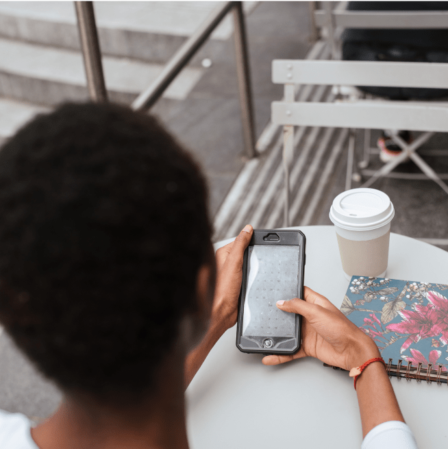 Woman sitting down at a table outside using her cellphone