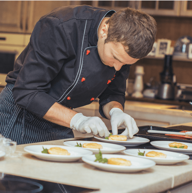 Chef in kitchen plating food