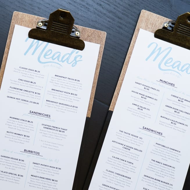 Two printed menus attached to wood with clips