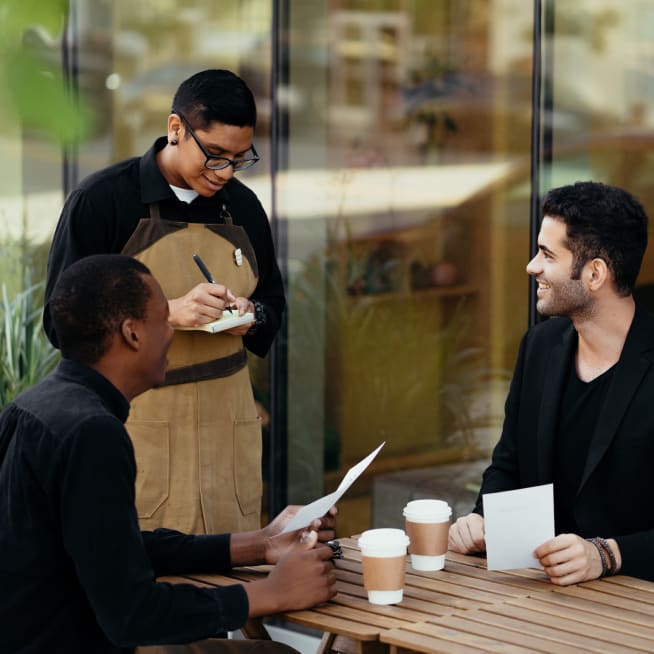 Waiter taking an order for two customer's sitting at a table