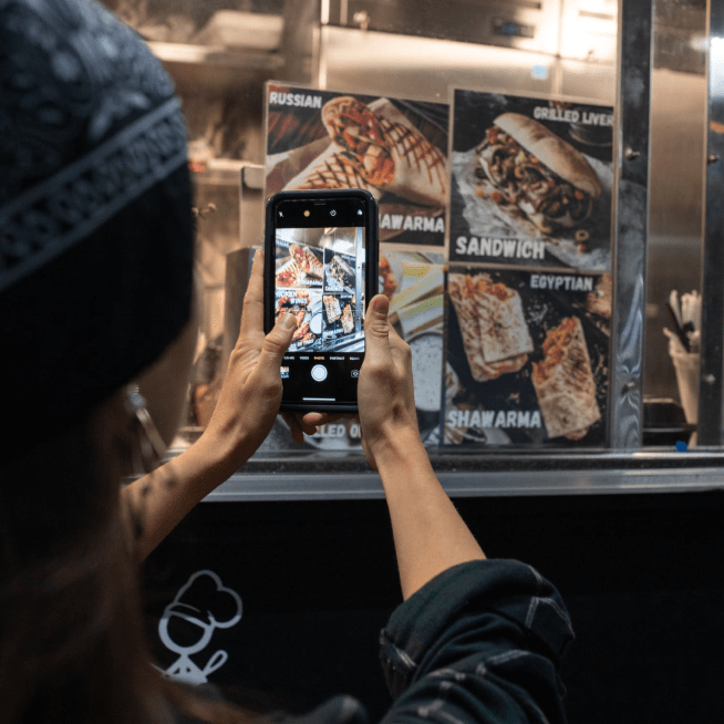 Women taking a photo of a restaurant menu in a window on her cellphone