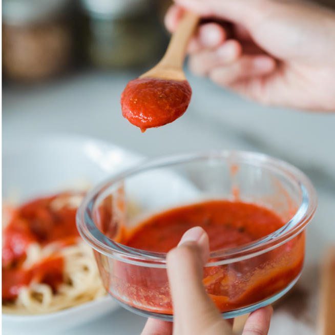 Chef adding tomato sauce to pasta dish