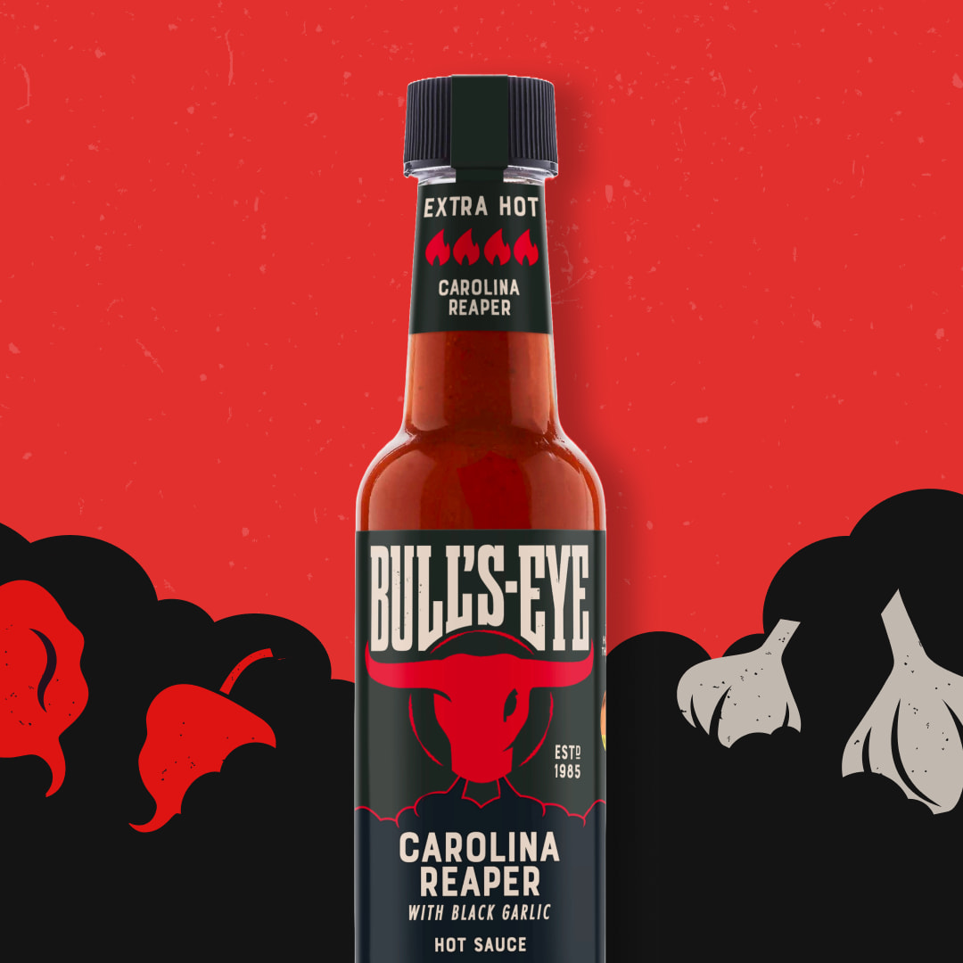 A bottle of Bull's-Eye Carolina Reaper hot sauce on a red and black background with hot peppers and garlic illustrations.