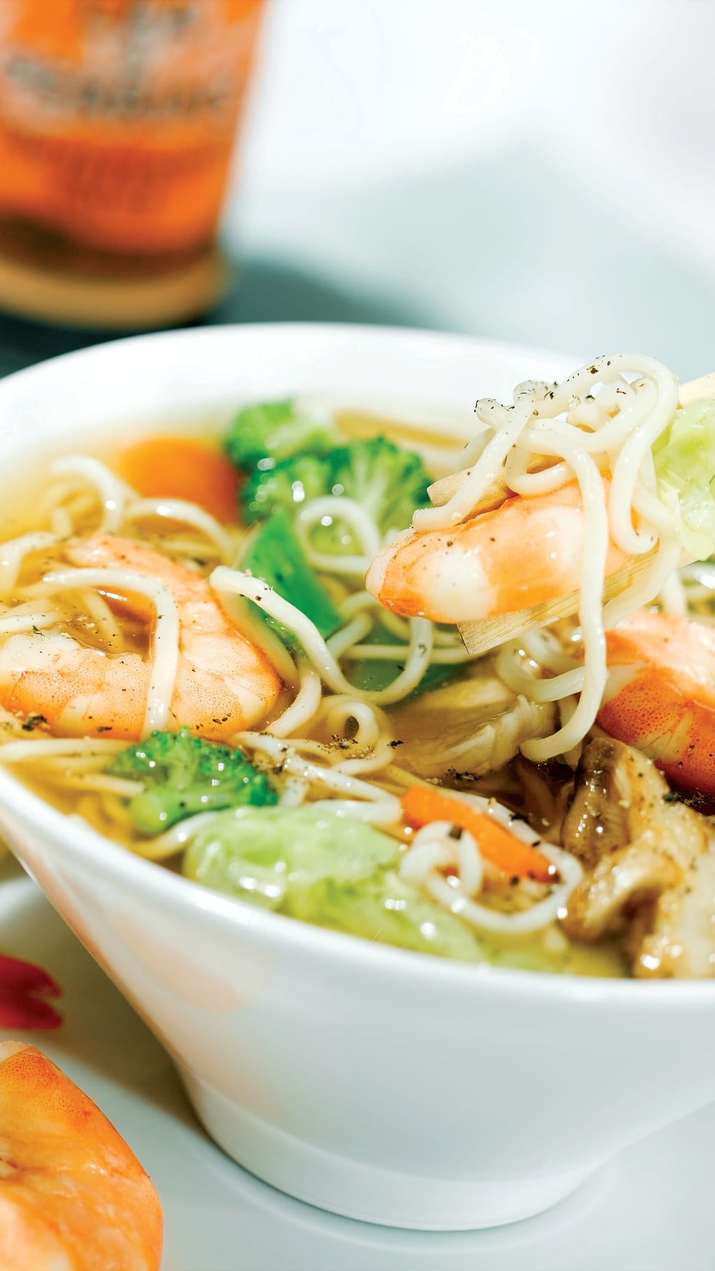 A bowl of shrimp and noodles with a pair of chopsticks.